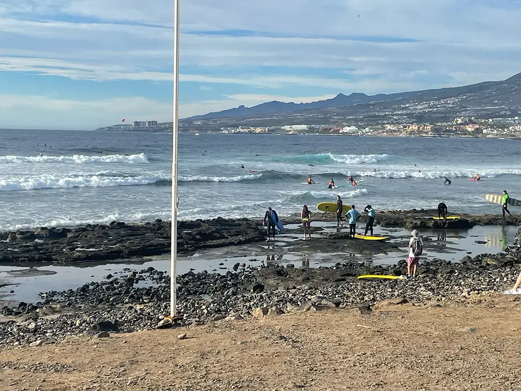 Beginner surfers entering the El Medio surf spot in Las Americas, Tenerife.