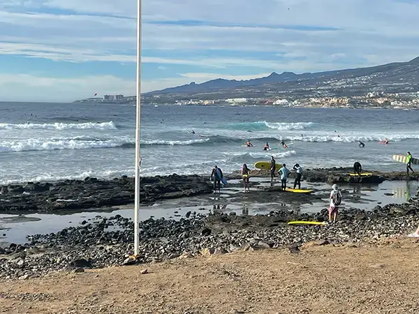 Beginner surfers entering the El Medio surf spot in Las Americas, Tenerife.